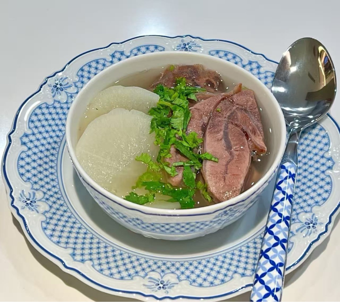 Clear soup with sliced radish, meat, and fresh herbs